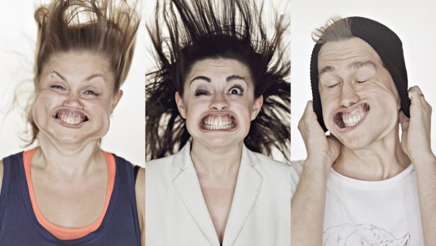 Drei Personen verziehen ihre Gesichter und blasen die Wangen auf.