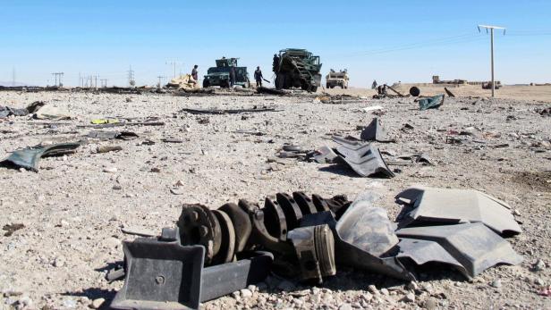 Auf einem Wüstenboden liegen Trümmerteile von Fahrzeugen.