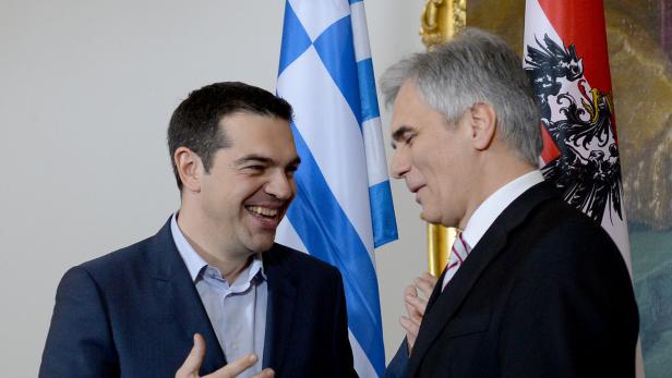 Alexis Tsipras und ein weiterer Mann unterhalten sich vor griechischen und österreichischen Flaggen.