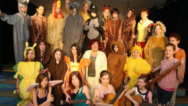 Eine Gruppe von Jugendlichen in Tierkostümen posiert auf einer Bühne.