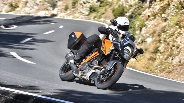 Ein Motorradfahrer fährt mit einer KTM auf einer kurvenreichen Straße.