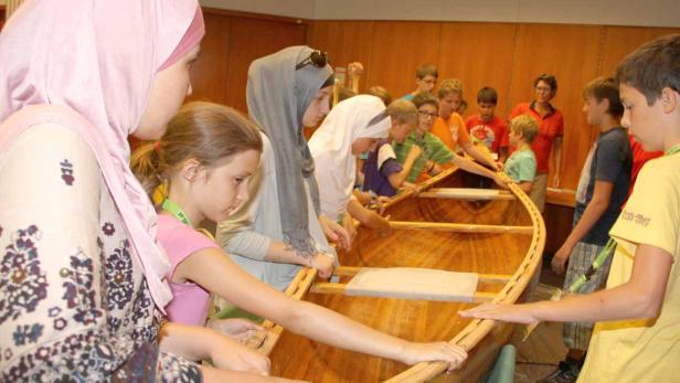 Eine Gruppe von Kindern baut gemeinsam ein Holzboot.
