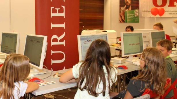 Kinder sitzen an Computern in einem Klassenzimmer.