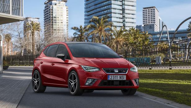 Ein roter Seat Ibiza vor einer Stadtkulisse mit Palmen und Hochhäusern.