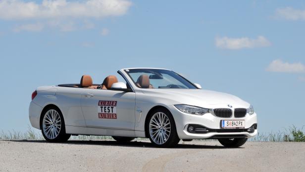 Ein weißes BMW 4er Cabriolet steht auf einer Schotterstraße.