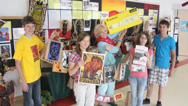 Eine Gruppe von Schülern präsentiert Kunstwerke und einen Scheck über 2.078,90 Euro.