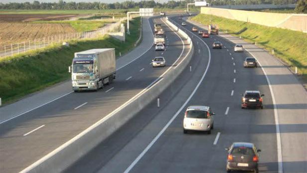 Ein LKW und mehrere PKWs fahren auf einer Autobahn.