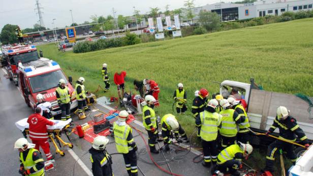 Nach einem Verkehrsunfall arbeiten Feuerwehrleute an einem verunglückten Fahrzeug.