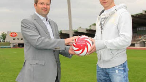 Zwei Männer stehen auf einem Fußballfeld und halten einen Ball.