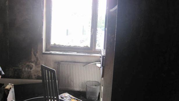 Ein Zimmer nach einem Brand mit verkohlten Wänden und einem Stuhl.