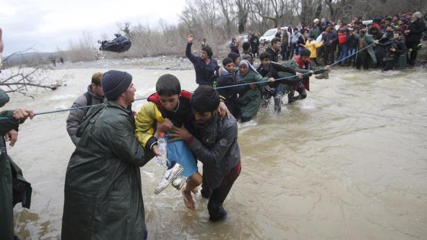 Migranten suchen durch einen Fluss den Weg nach Mazedonien.