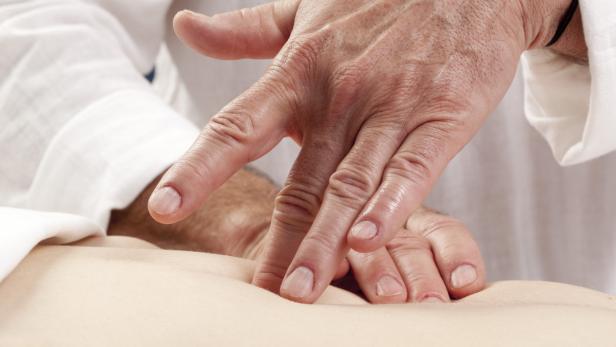 Ein Arzt untersucht den Bauch eines Patienten mit seinen Händen.