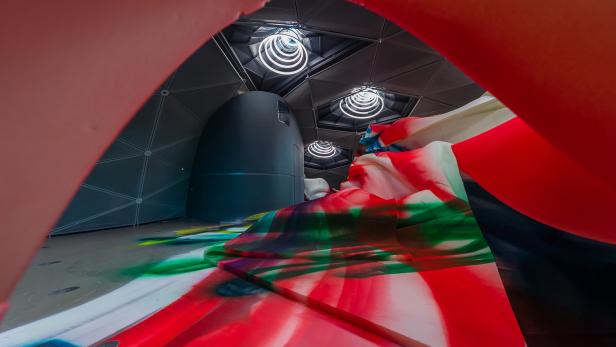 Eine Installation mit farbigen Projektionen in einem futuristisch anmutenden Raum.