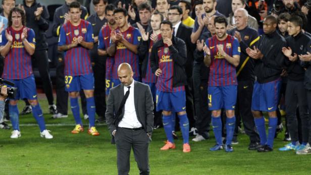 Pep Guardiola steht mit gesenktem Kopf vor einer Reihe applaudierender Barcelona-Spieler.