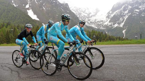 Vier Radrennfahrer des Teams Astana fahren auf einer Straße in den Bergen.