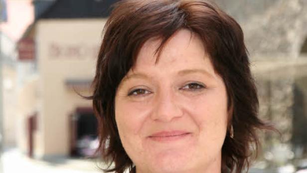 Eine Frau mit braunen Haaren lächelt in die Kamera.