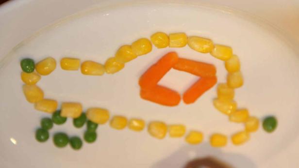 Ein Auto aus Erbsen, Mais und Karotten auf einem Teller.