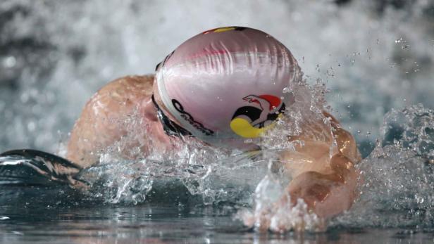 Ein Schwimmer mit Badekappe zieht seine Bahnen im Wasser.