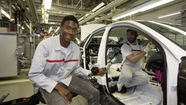 Zwei Arbeiter montieren in einer Fabrik einen weißen Audi.