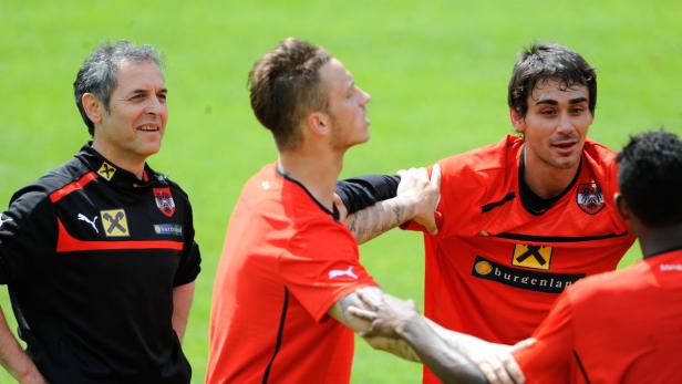 Ein Trainer und mehrere Fußballspieler des österreichischen Nationalteams stehen auf dem Trainingsplatz.