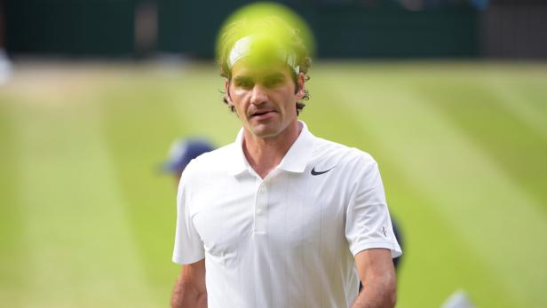 Roger Federer auf einem Tennisplatz, mit einem Tennisball im Vordergrund.