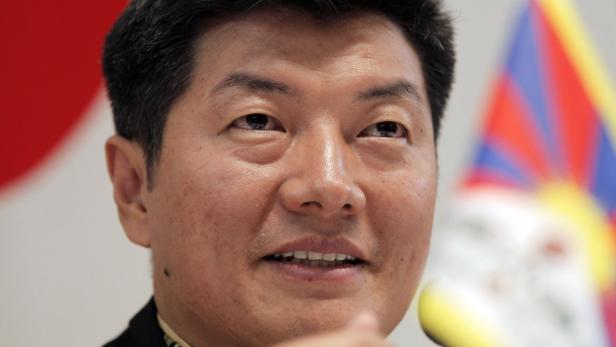 Ein Porträt von Sikyong Penpa Tsering vor der tibetischen Flagge.
