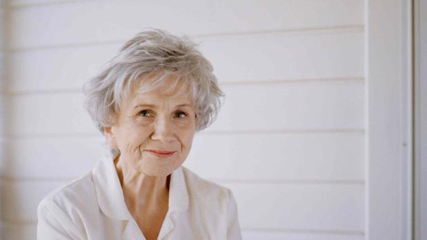 Eine ältere Frau mit grauen Haaren lächelt in die Kamera.