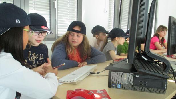 Eine Gruppe von Schülerinnen arbeitet an Computern in einem hellen Raum.