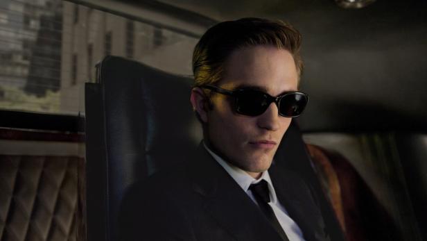Robert Pattinson sitzt mit Sonnenbrille in einem Auto.