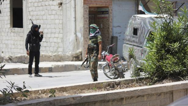Zwei bewaffnete Männer stehen auf einer Straße in einer Stadt.
