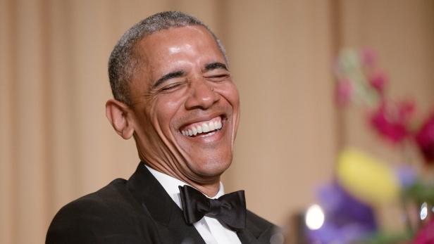 Barack Obama lacht mit geschlossenen Augen und zeigt seine Zähne.