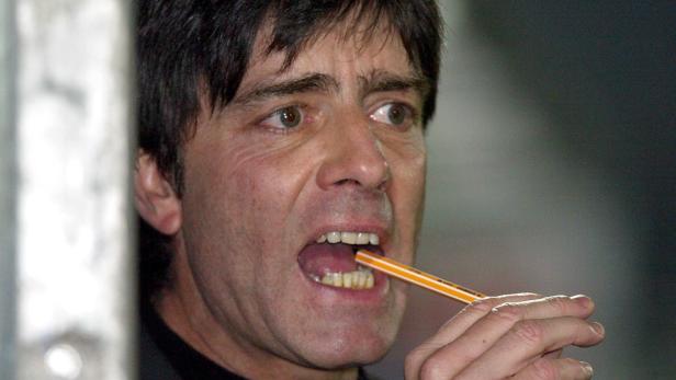 Joachim Löw hält einen Stift zwischen den Zähnen.