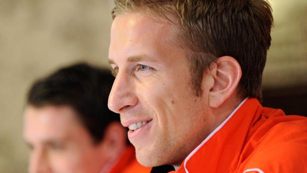 Ein Mann mit blonden Haaren und einem orangefarbenen Hemd lächelt.