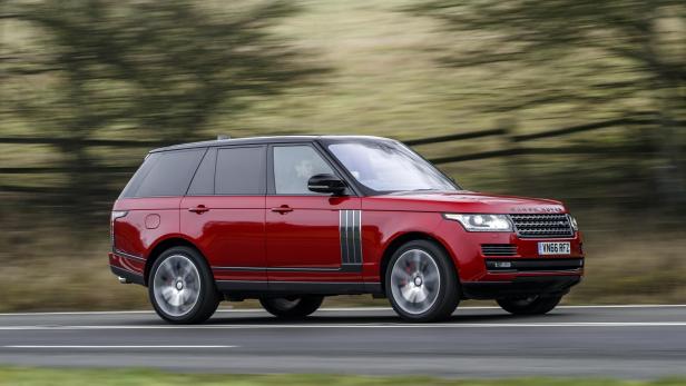 Ein roter Range Rover fährt auf einer Landstraße.