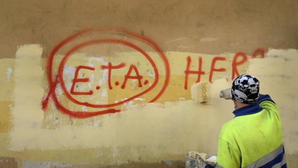 Eine Person übermalt mit einer Farbrolle Graffiti an einer Wand, darunter die Buchstaben „ETA“.