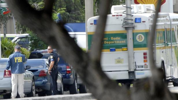 Ein FBI-Agent und ein Polizist stehen neben einem Bus des Miami-Dade Police Department.