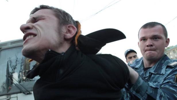 Ein Mann wird von Polizisten abgeführt und scheint sich zu wehren.
