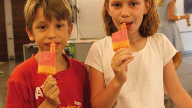 Ein Junge und ein Mädchen essen ein Eis in Form einer Hand.