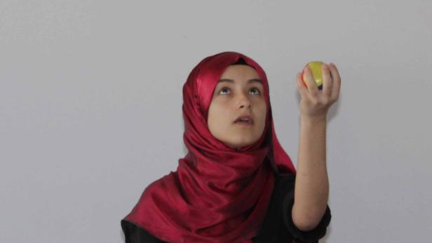 Eine junge Frau mit Hijab jongliert mit drei Bällen.