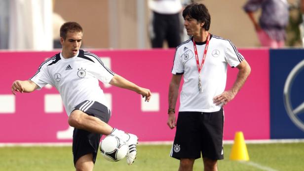 Philipp Lahm jongliert mit einem Fußball, während Joachim Löw zusieht.