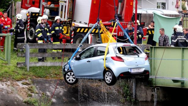 Ein beschädigtes Auto wird von der Feuerwehr aus einem Fluss geborgen.