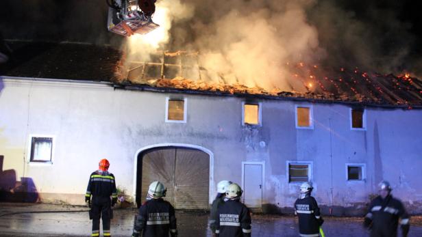 Feuerwehrleute beobachten ein brennendes Gebäude in der Nacht.