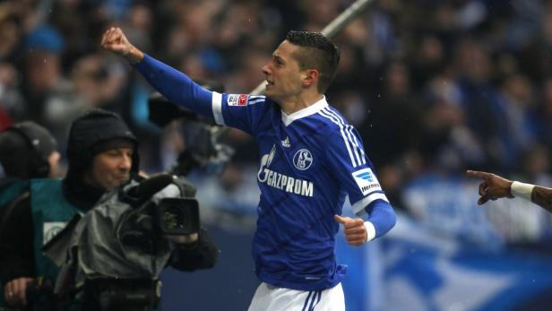 Ein Fußballspieler im blauen Trikot von Schalke 04 jubelt mit erhobener Faust.