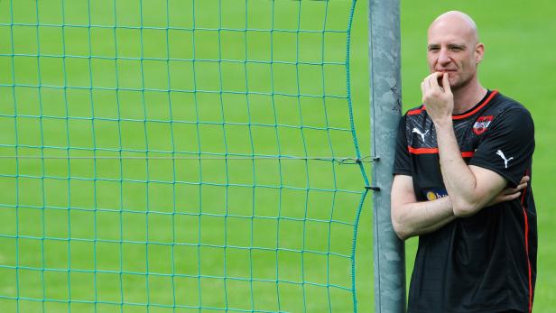 Ein Mann im Österreich-Trikot steht nachdenklich am Fußballtor.