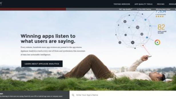 Ein Mann liegt im Gras und betrachtet die Applause-Analytik auf seinem Smartphone.