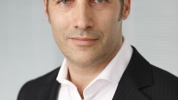 Ein Mann mit dunklen Haaren und einem dunklen Anzug blickt in die Kamera.