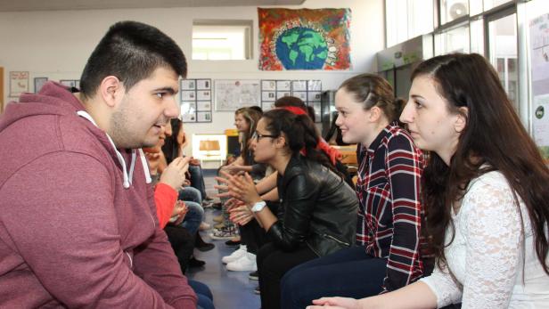 Eine Gruppe junger Leute sitzt im Kreis und unterhält sich angeregt.
