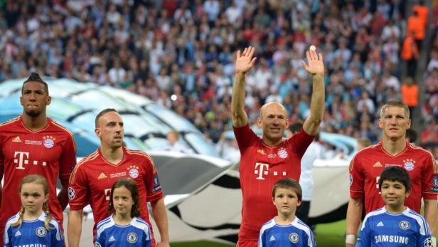 Fußballspieler des FC Bayern München vor einem Spiel mit Kindern im Chelsea-Trikot.