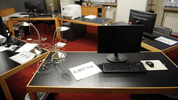 Mehrere Schreibtische mit Computern und Papieren der Parteien FPÖ und Grüne.