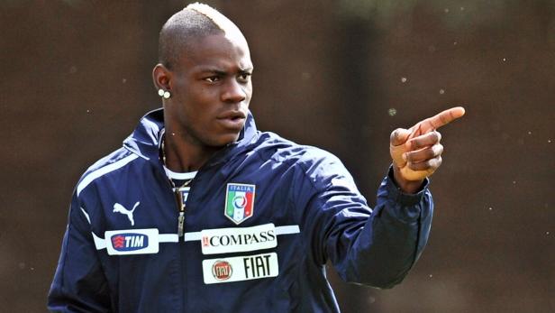 Mario Balotelli in Trainingsjacke der italienischen Nationalmannschaft zeigt mit dem Finger.